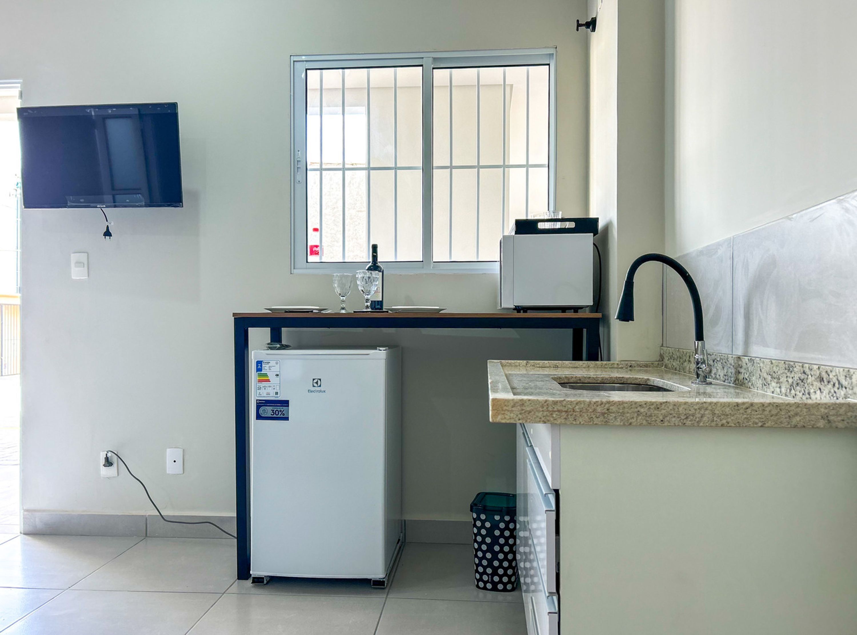 A compact kitchen with a refrigerator, a microwave, a sink, and a window.