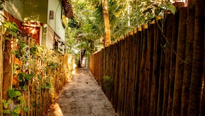 Un estrecho callejón con una valla de madera a un lado y un muro de ladrillo al otro, que conduce a la entrada de un edificio.