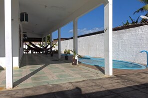 A covered outdoor area with a pool, potted plants, and a white wall. - Casa c Piscina a 300m da Praia do Po o Cabedelo PB (Cabedelo)