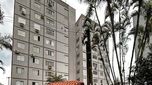 Ein mehrstöckiges Gebäude mit einem kleinen, umzäunten Innenhof, der ein Tor und einen überdachten Bau mit Ziegeldach zeigt.