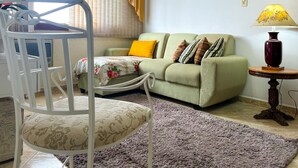 Ein Wohnzimmer mit einem grünen Sofa, einem weißen Sessel, einem kleinen Tisch und einer Lampe.