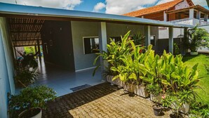 Ein modernes Haus mit überdachter Terrasse, Kübelpflanzen und einem gepflegten Rasen.
