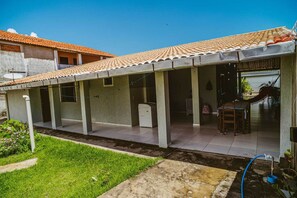 A house with a tiled roof, a covered patio, and a small garden area.