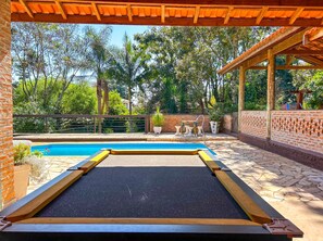 A pool area with a wooden deck, a brick wall, and a pergola. - Ch Cara com Piscina e Churrasq em Botucatu SP (Botucatu)