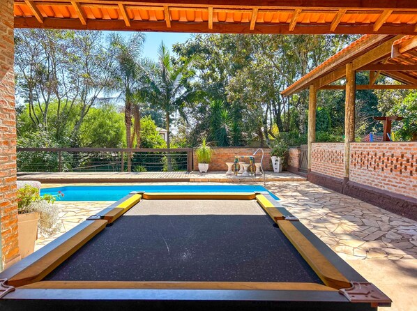 A pool area with a wooden deck, a brick wall, and a pergola.