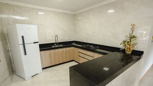 A modern kitchen with a white refrigerator, black countertops, and wooden cabinets.