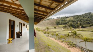 A covered outdoor area with a view of a river and hills.