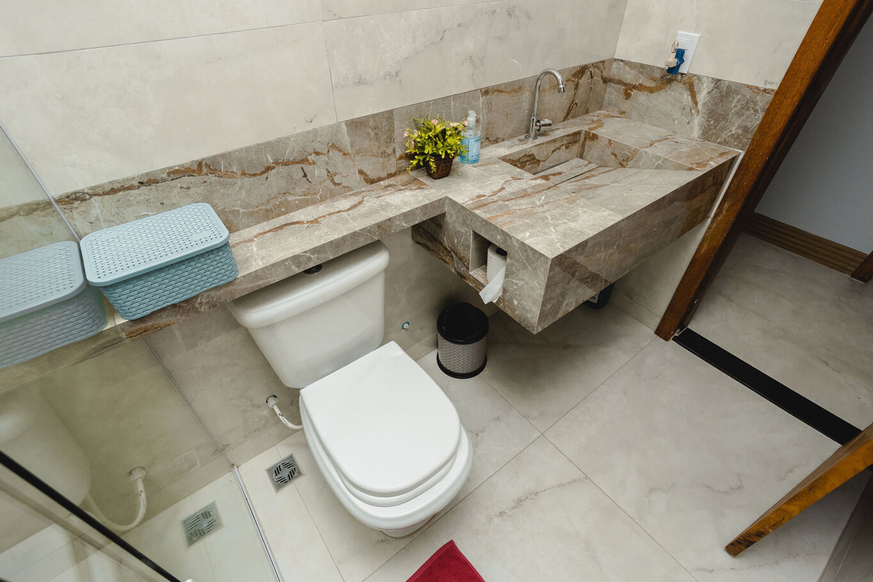 A bathroom with a marble sink, a toilet, a shower, and a glass-enclosed shower area.