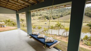 A hammock swing with cushions, overlooking a lake and forested hills.