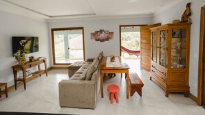 A spacious living room with a sectional sofa, a wooden dining table, and a red stool.