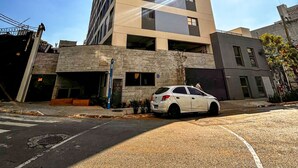 A tall, modern building with a parking lot in front. - Apto Confort vel com Wifi no Centro da Bela Vista (São Paulo)