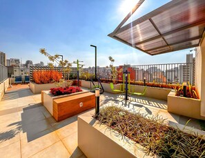 A rooftop terrace with outdoor seating, exercise equipment, and planters with various plants. - Apto Confort vel com Wifi no Centro da Bela Vista (São Paulo)