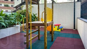 A children's play area with a wooden climbing structure, a slide, and colorful steps. - Apto Confort vel com Wifi no Centro da Bela Vista (São Paulo)