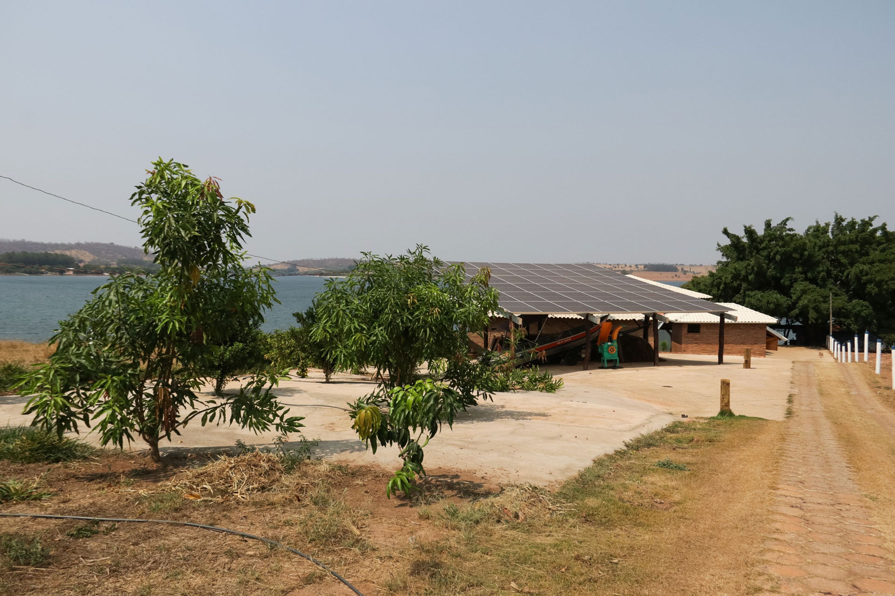 Un edificio con techo de paneles solares, rodeado de árboles y un camino de tierra.