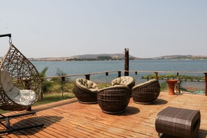 A wooden deck with wicker furniture overlooking a body of water. - Chal com Vista e Acesso ao Rio Grande - MG (Delfinopolis)