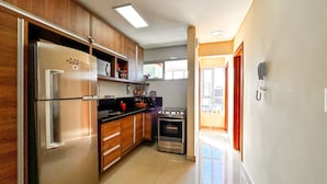 A modern kitchen with wooden cabinets, stainless steel appliances, and a view to the outside. - Apto Aconchegante c Wifi Ar-condicionado e Garagem (Salvador)
