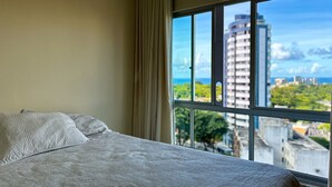 A hotel room with a large window offering a city view. - Apto Aconchegante c Wifi Ar-condicionado e Garagem (Salvador)