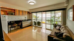 A modern kitchen with a dining area and a large sliding glass door leading to a balcony with a view of the ocean.
