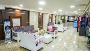 Een hotel lobby met zithoeken, een receptiebalie en een digitale informatiezuil.