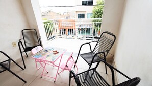 Un balcon avec une table et des chaises, une vue sur les bâtiments et une balustrade.
