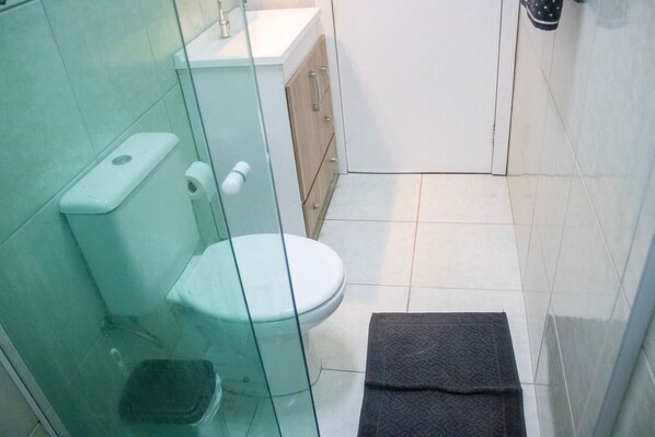 Une petite salle de bain comprenant des toilettes, une douche à parois de verre et un lavabo.