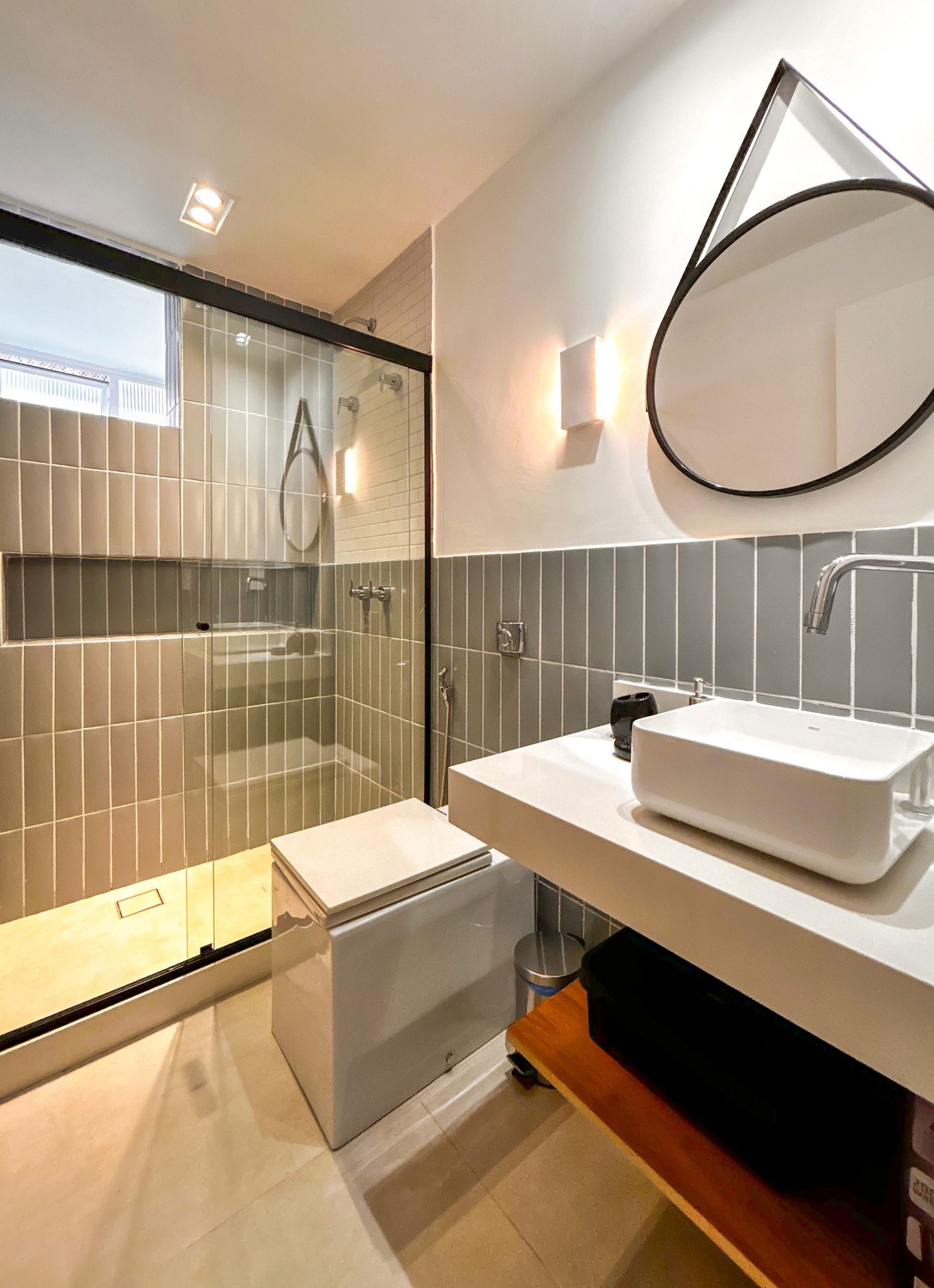 A modern bathroom with a glass-enclosed shower, a white sink, and a large mirror.