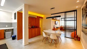 A modern kitchen with a dining area, featuring a large table and chairs, a built-in oven, and a view through a glass door. - Timo Apto 350m da Praia de Copacabana RJ (Rio de Janeiro)