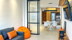 A modern living room with a sofa, a bean bag, a dining area with a table and chairs, and a kitchen in the background. - Timo Apto 350m da Praia de Copacabana RJ (Rio de Janeiro)