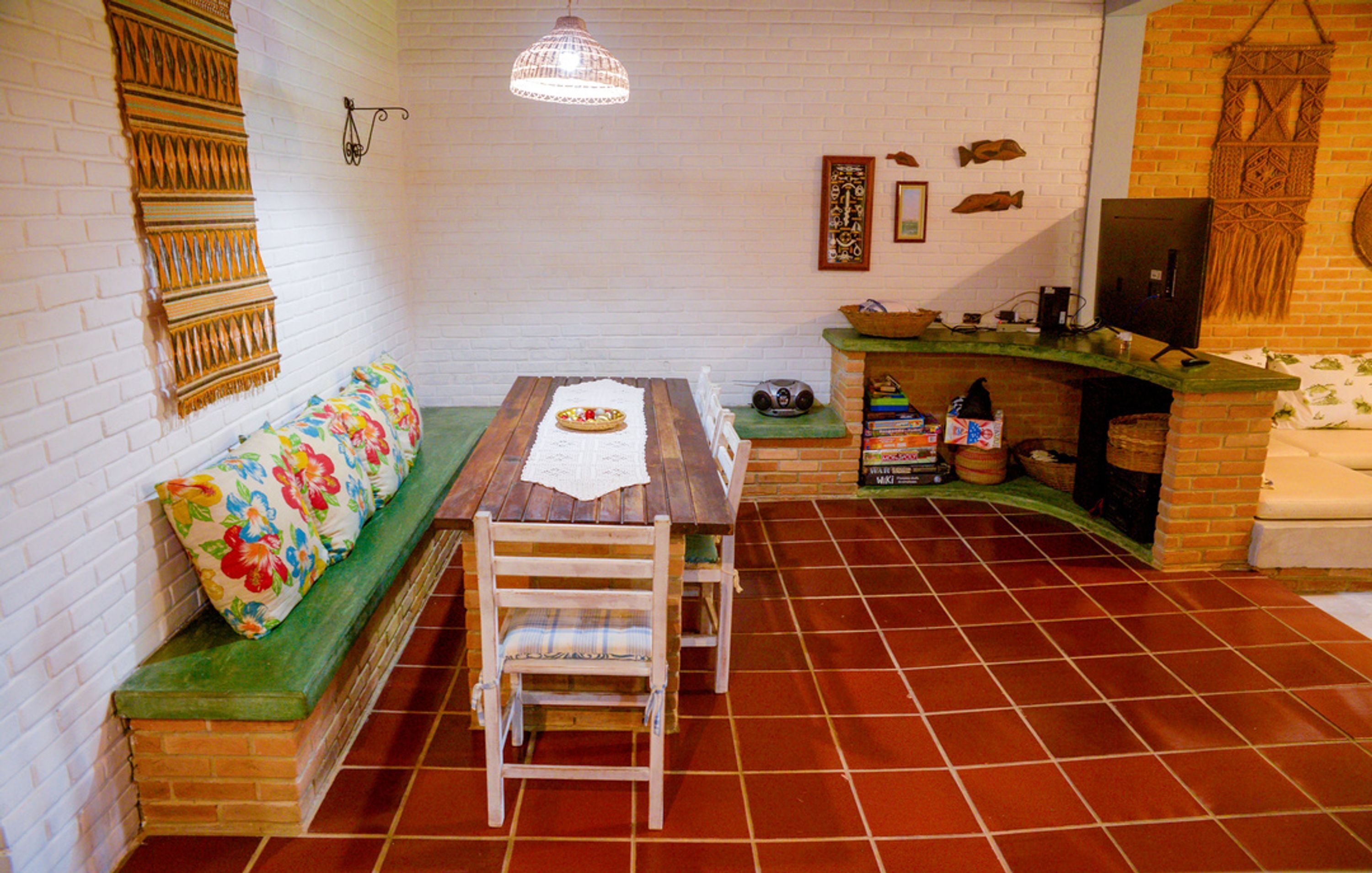 A cozy room with a wooden table, bench, and a brick fireplace.