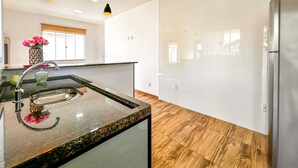 A modern kitchen with a granite countertop, stainless steel appliances, and wooden flooring. - Casa a Poucos Metros da Praia do Coral - Cabo Frio (Cabo Frio)