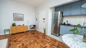 A modern kitchen with a herringbone wooden floor, a stainless steel refrigerator, and light blue cabinets. - Apto com Excelente Localiza o em Asa Sul DF (Brasília)