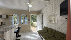 Ett kök med en bänkskiva i marmor, en svart stol och en grön soffa. Det finns tre fönster med dekorativt glas, en takfläkt och en dörr som leder ut.