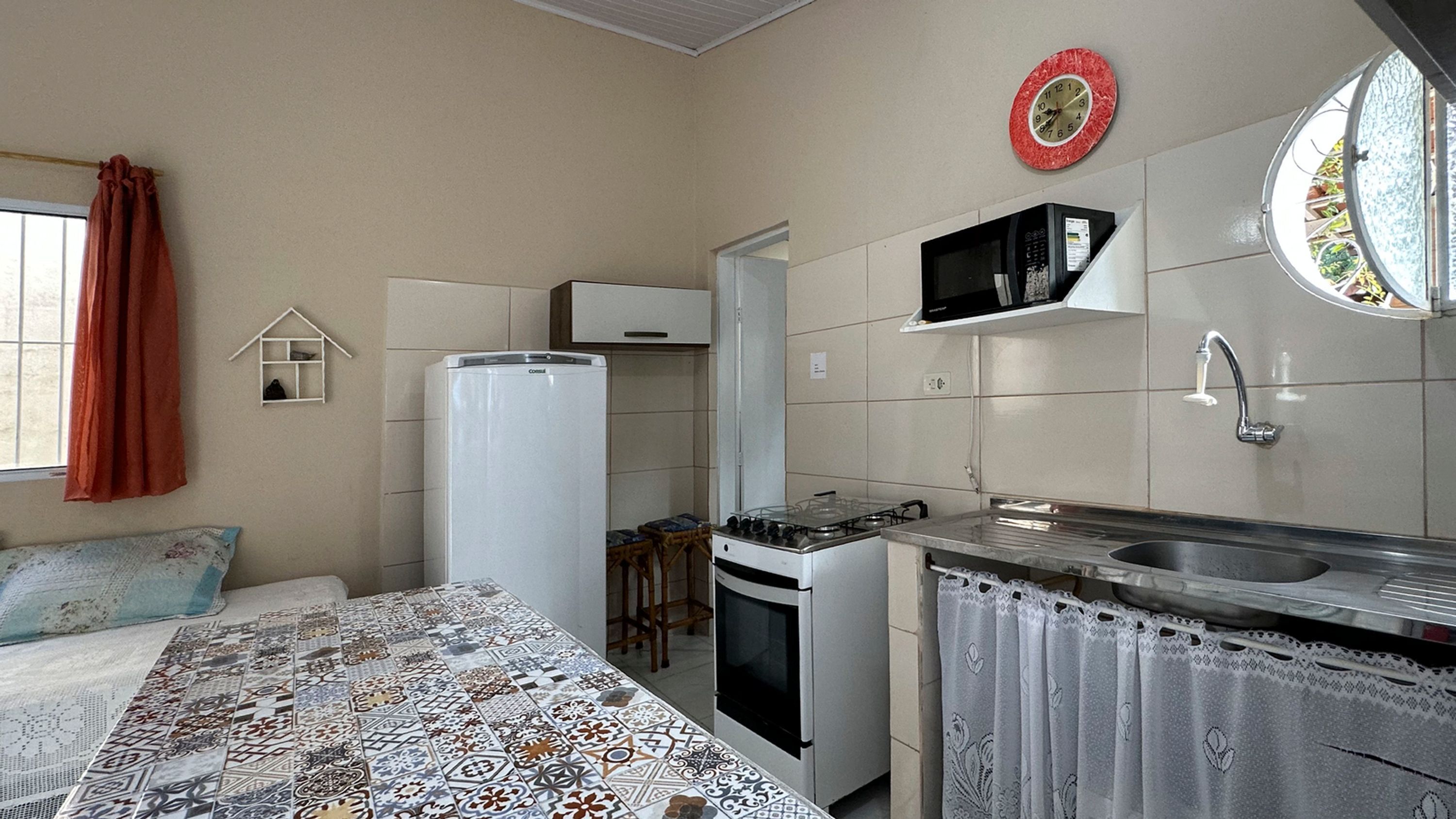 A compact kitchen with a refrigerator, stove, microwave, and sink.