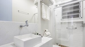 Une salle de bain moderne avec un lavabo rectangulaire, des toilettes et une douche séparée par une paroi de verre.