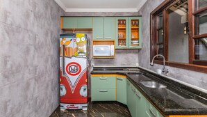 Una cucina con mobili verdi, un frigorifero rosso e un forno a microonde.