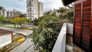 Blick von einem Balkon auf eine Skyline mit modernen Gebäuden, einer Straße und etwas Grün.