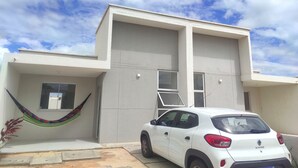 A modern building with a white exterior, a visible window, and a white car parked in front.