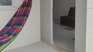 A room with a hammock, a window, and an open door leading to another room.