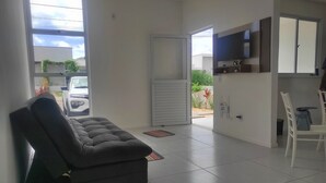 A modern living room with a sofa, a TV mounted on the wall, and a sliding glass door leading to a patio.
