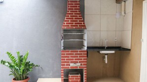A compact kitchen with a brick oven, a sink, and a potted plant.