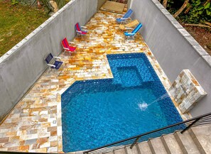 A swimming pool with a tiled deck and lounge chairs.
