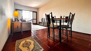 A dining area with a table and chairs, a ceiling fan, a lamp, and a view of a balcony. - Apto a 210m da Praia da Pontinha em Araruama RJ (Araruama)