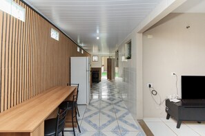 Une cuisine moderne avec un mur recouvert de panneaux en bois, un coin repas avec une table et des chaises en bois, et un meuble pour la télévision avec un téléviseur à écran plat.