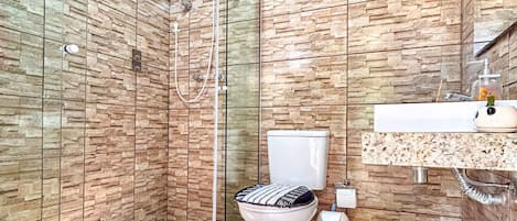 A modern bathroom with a glass shower enclosure, a toilet, and a sink with a marble countertop.