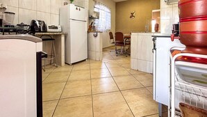 Una cocina con armarios blancos, un refrigerador, una estufa y un lavamanos. Hay un comedor con una mesa y sillas.
