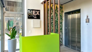 A modern interior with a reception desk, a sign reading "NEX ONE," and an elevator. - Timo Apto a 900m do Parque Ibirapuera com Wifi SP (São Paulo)