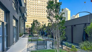 A modern urban courtyard with seating areas, a small tree, and a bike rack. - Timo Apto a 900m do Parque Ibirapuera com Wifi SP (São Paulo)