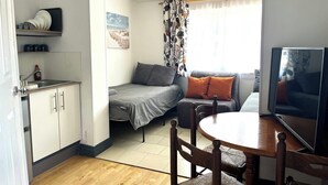 Ein kompakter Wohnraum mit Küchenzeile, einem Bett, einer Couch und einem Essbereich.