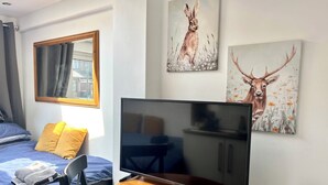 Ein Hotelzimmer mit einem Bett, einem Fernseher auf einem Holzbalken und zwei Bildern an der Wand.