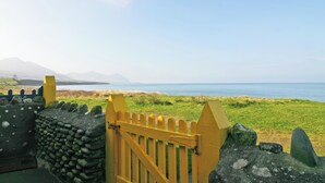 A coastal view with a wooden gate leading to a grassy area.